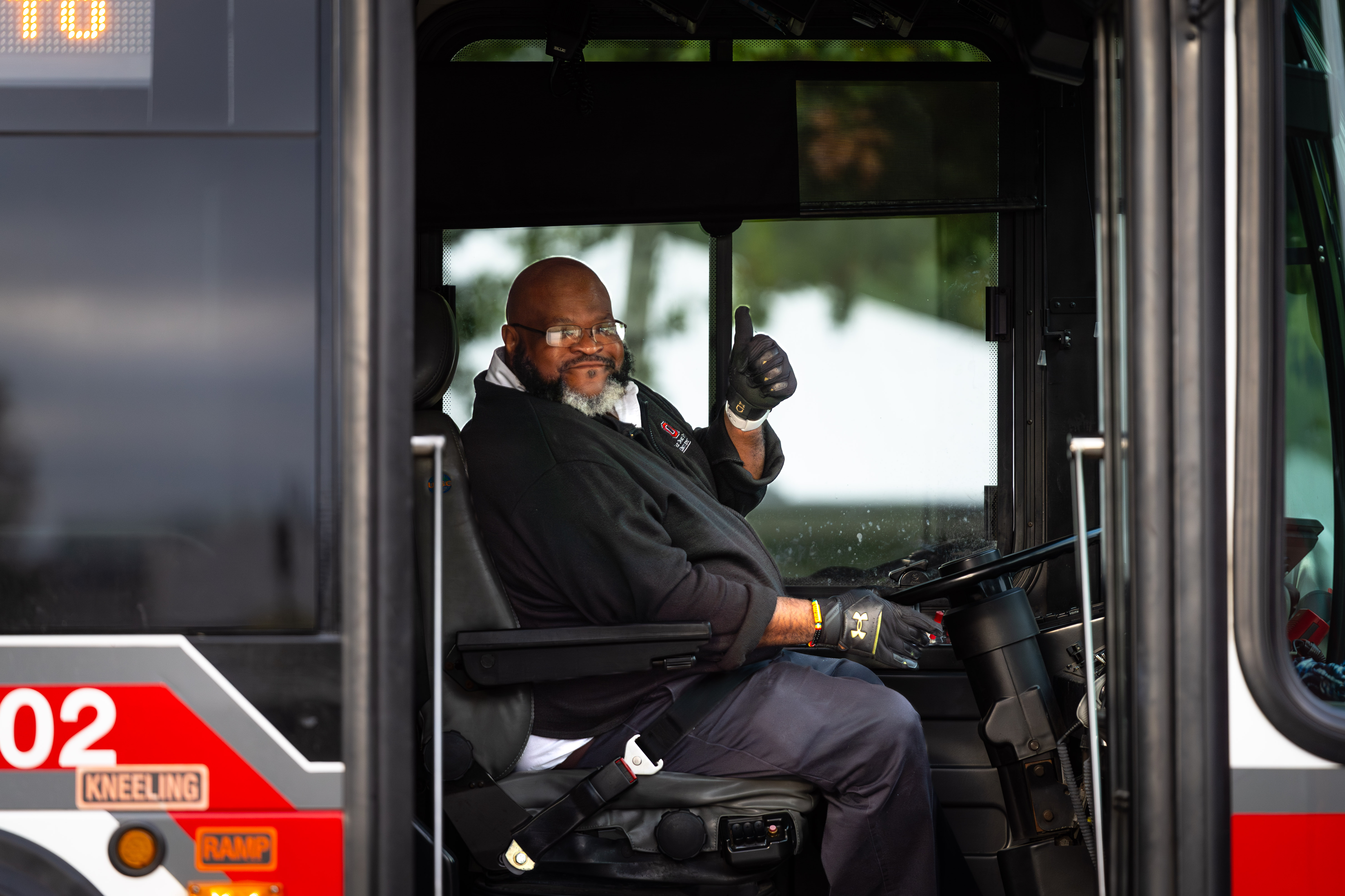 CABS driver in driver's seat of bus giving thumbs up gesture