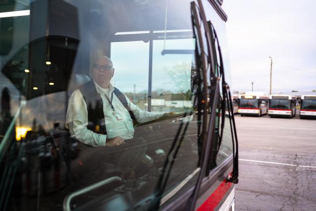 CABS bus driver sitting in driver's seat as seen through front windshield