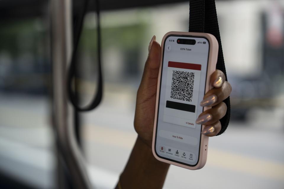 Hand holding phone displaying the QR code to scan.